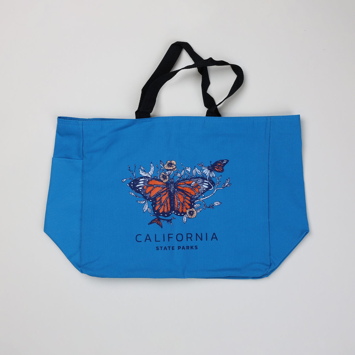 a blue tote bag featuring three monarch butterflies surrounded by flowers