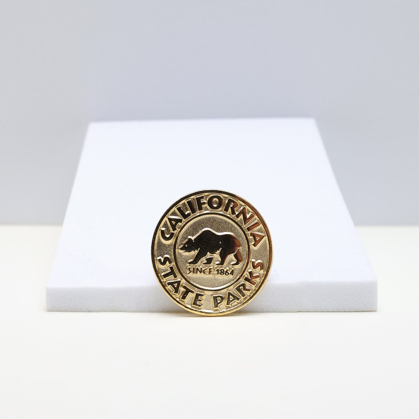 a circle gold pin with a grizzly bear in the center, surrounded by the words California State Parks
