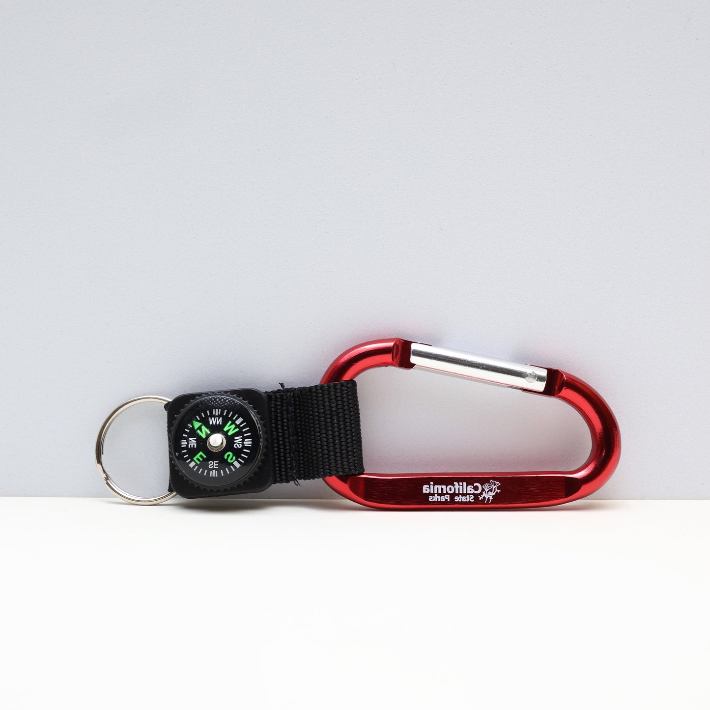 a small compass attached to a red carabiner