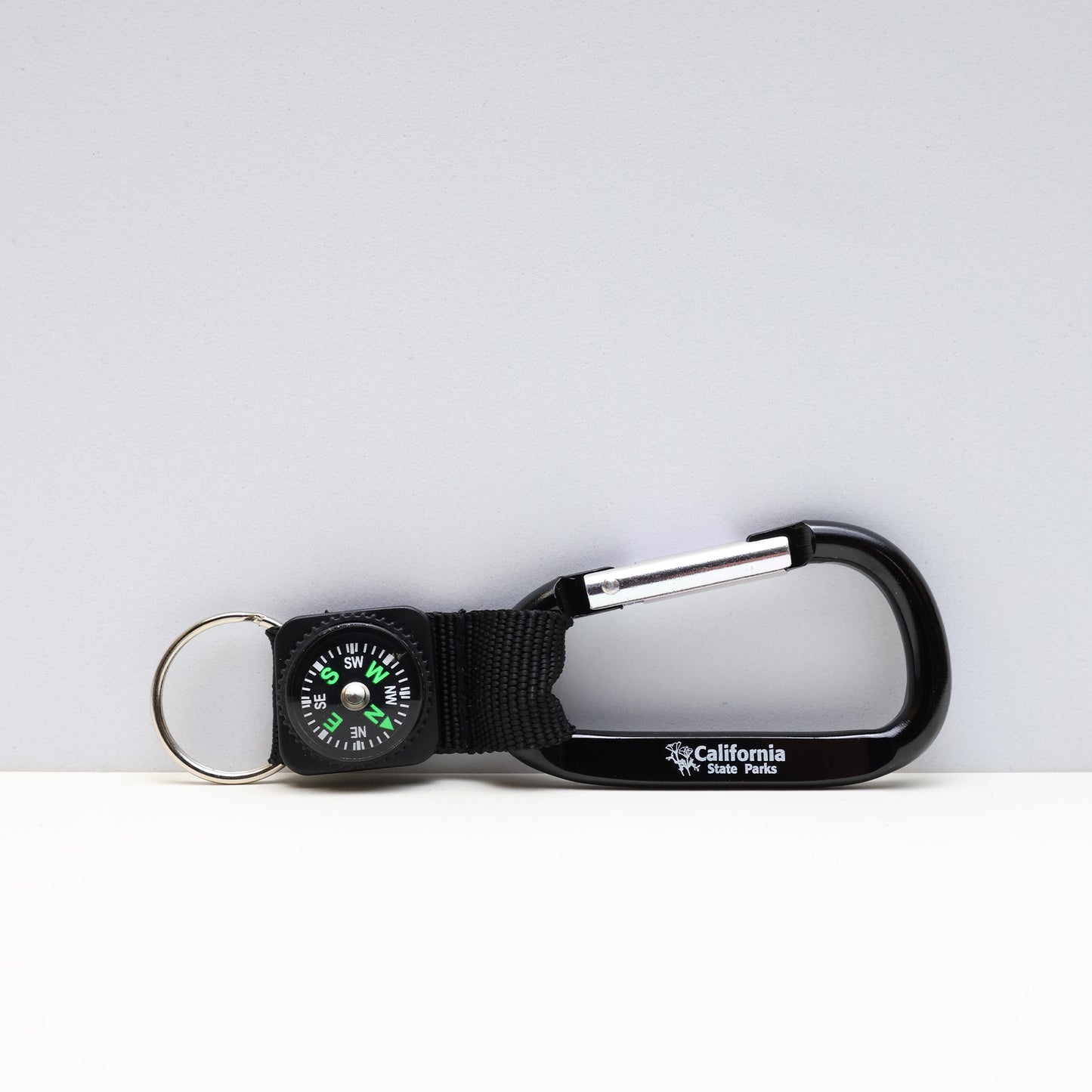 a small compass attached to a black carabiner