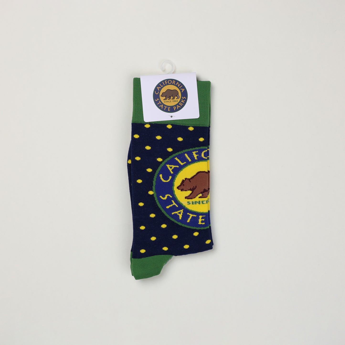 a pair of folded navy blue socks with yellow spots, a green cuff, and a California State Parks logo