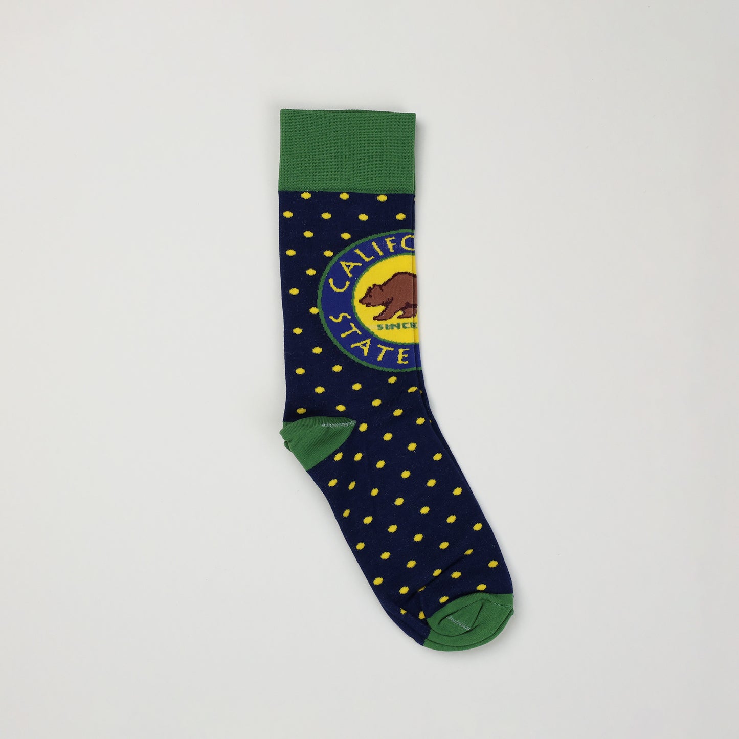 a side view of a navy blue sock with yellow spots, a green toe and heel, a green cuff, and a California State Parks logo