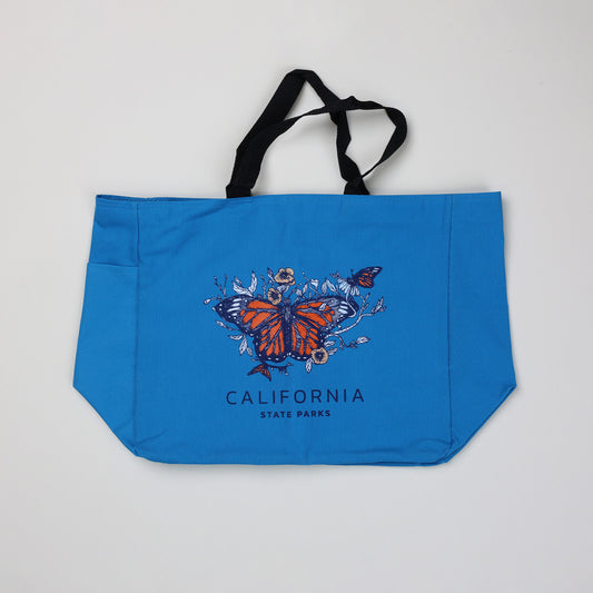 a blue tote bag featuring three monarch butterflies surrounded by flowers