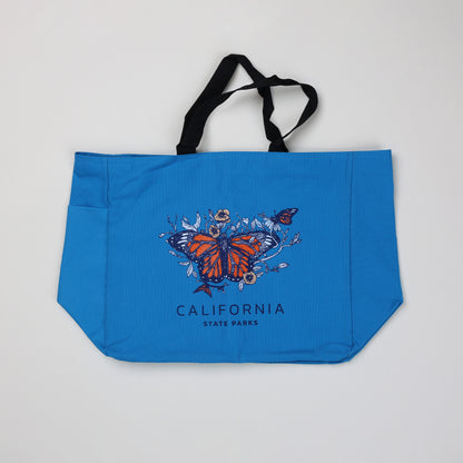 a blue tote bag featuring three monarch butterflies surrounded by flowers