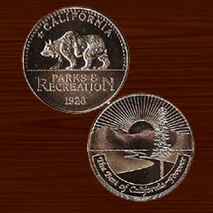 the front and back of the California State Parks medallion, with a grizzly bear on the front and a Redwood tree and sunset on the back