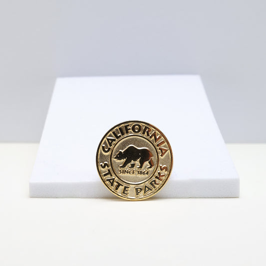 a circle gold pin with a grizzly bear in the center, surrounded by the words California State Parks