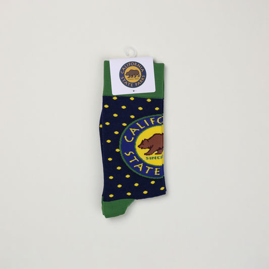 a pair of folded navy blue socks with yellow spots, a green cuff, and a California State Parks logo